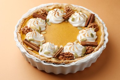 Delicious homemade pumpkin pie in baking dish on orange table, closeup