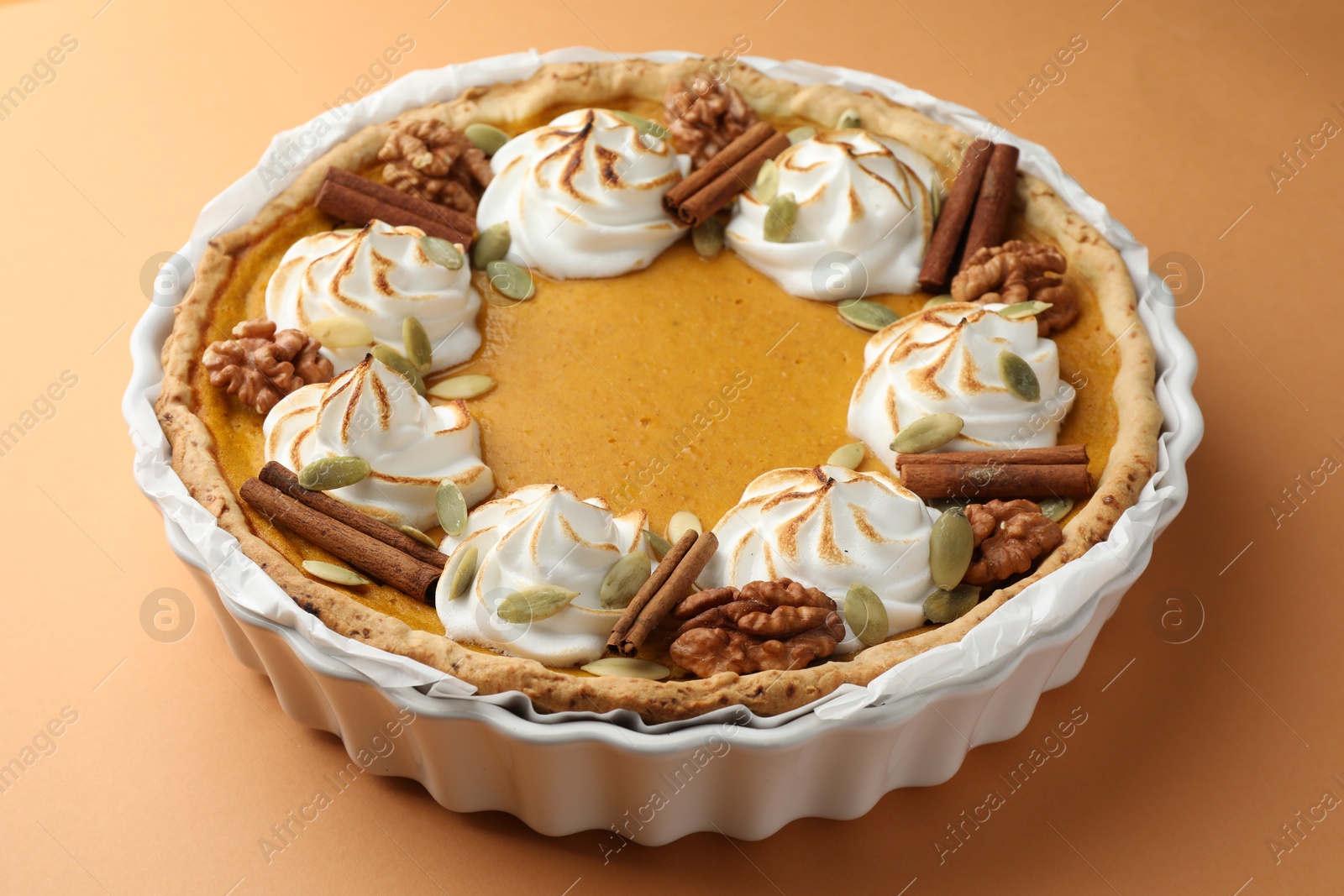 Photo of Delicious homemade pumpkin pie in baking dish on orange table, closeup