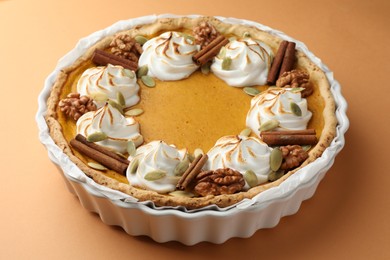 Photo of Delicious homemade pumpkin pie in baking dish on orange table, closeup