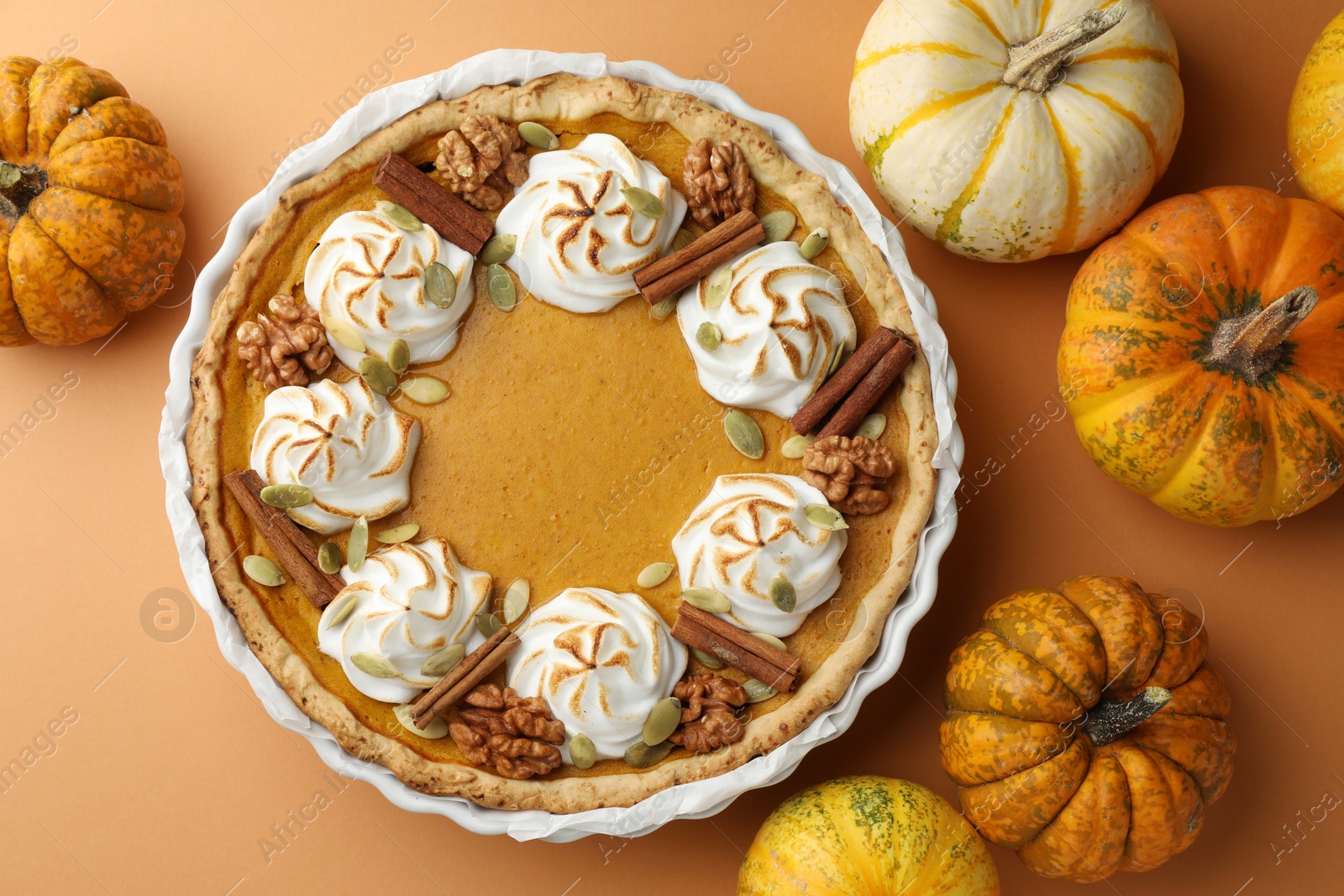 Photo of Delicious homemade pumpkin pie in baking dish and fresh pumpkins on orange table, flat lay