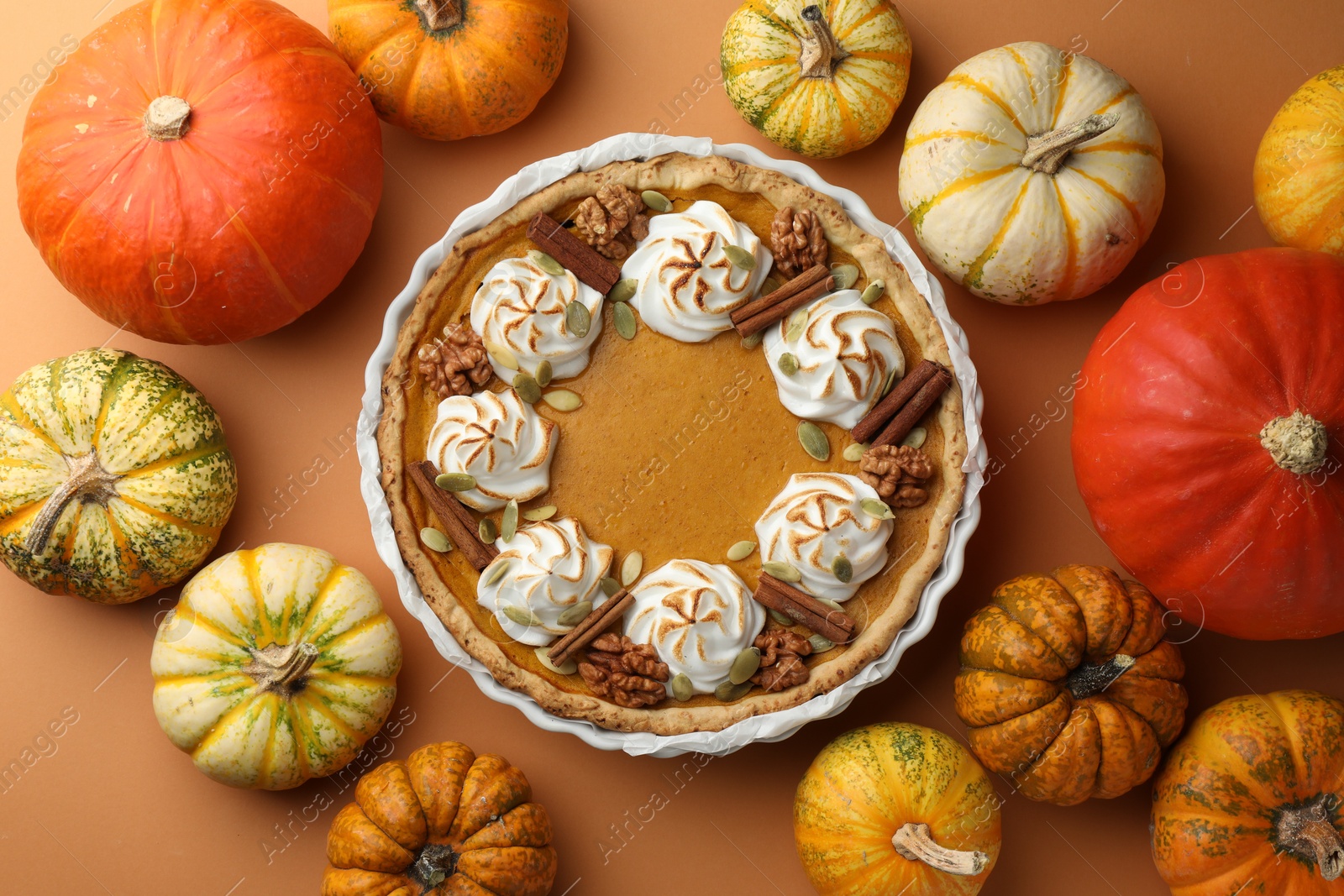 Photo of Delicious homemade pumpkin pie in baking dish and fresh pumpkins on orange table, flat lay