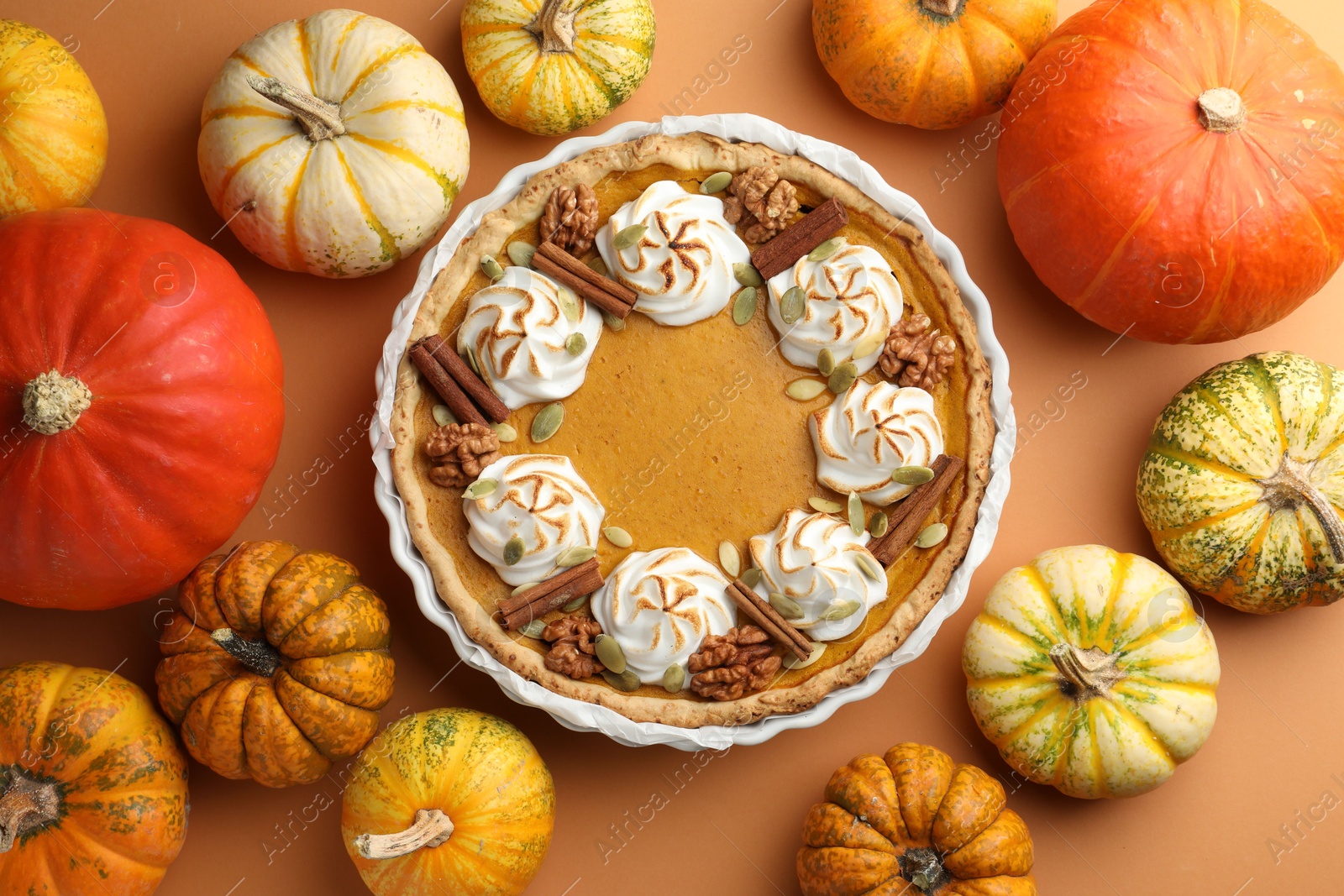 Photo of Delicious homemade pumpkin pie in baking dish and fresh pumpkins on orange table, flat lay