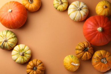 Frame made of different ripe pumpkins on orange background, flat lay. Space for text