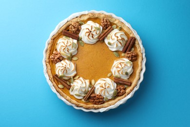 Tasty homemade pumpkin pie in baking dish on light blue table, top view