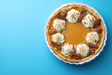 Tasty homemade pumpkin pie in baking dish on light blue table, top view. Space for text