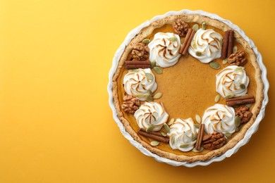 Tasty homemade pumpkin pie in baking dish on orange table, top view. Space for text