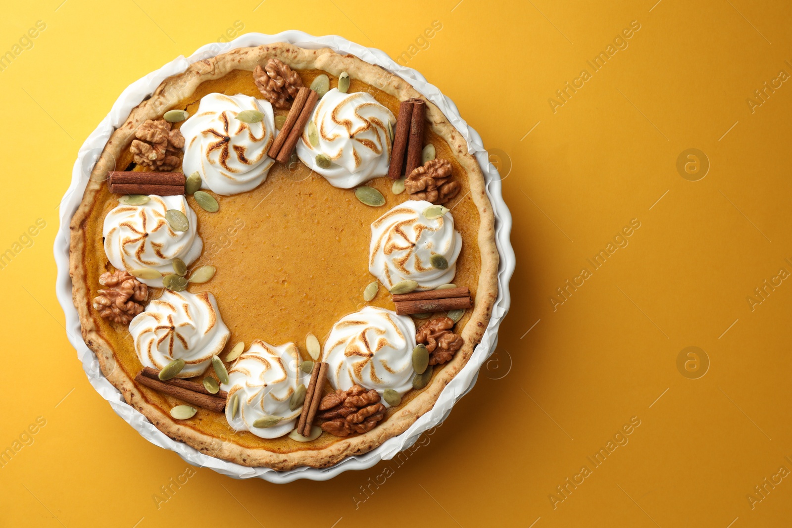 Photo of Tasty homemade pumpkin pie in baking dish on orange table, top view. Space for text