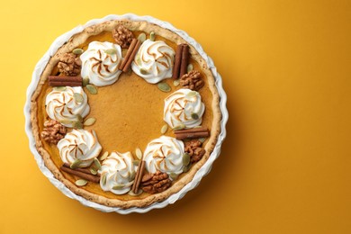 Tasty homemade pumpkin pie in baking dish on orange table, top view. Space for text