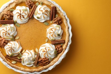 Photo of Tasty homemade pumpkin pie in baking dish on orange table, top view. Space for text