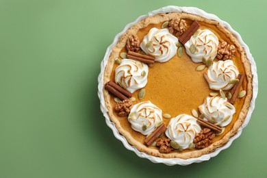 Photo of Tasty homemade pumpkin pie in baking dish on green table, top view. Space for text