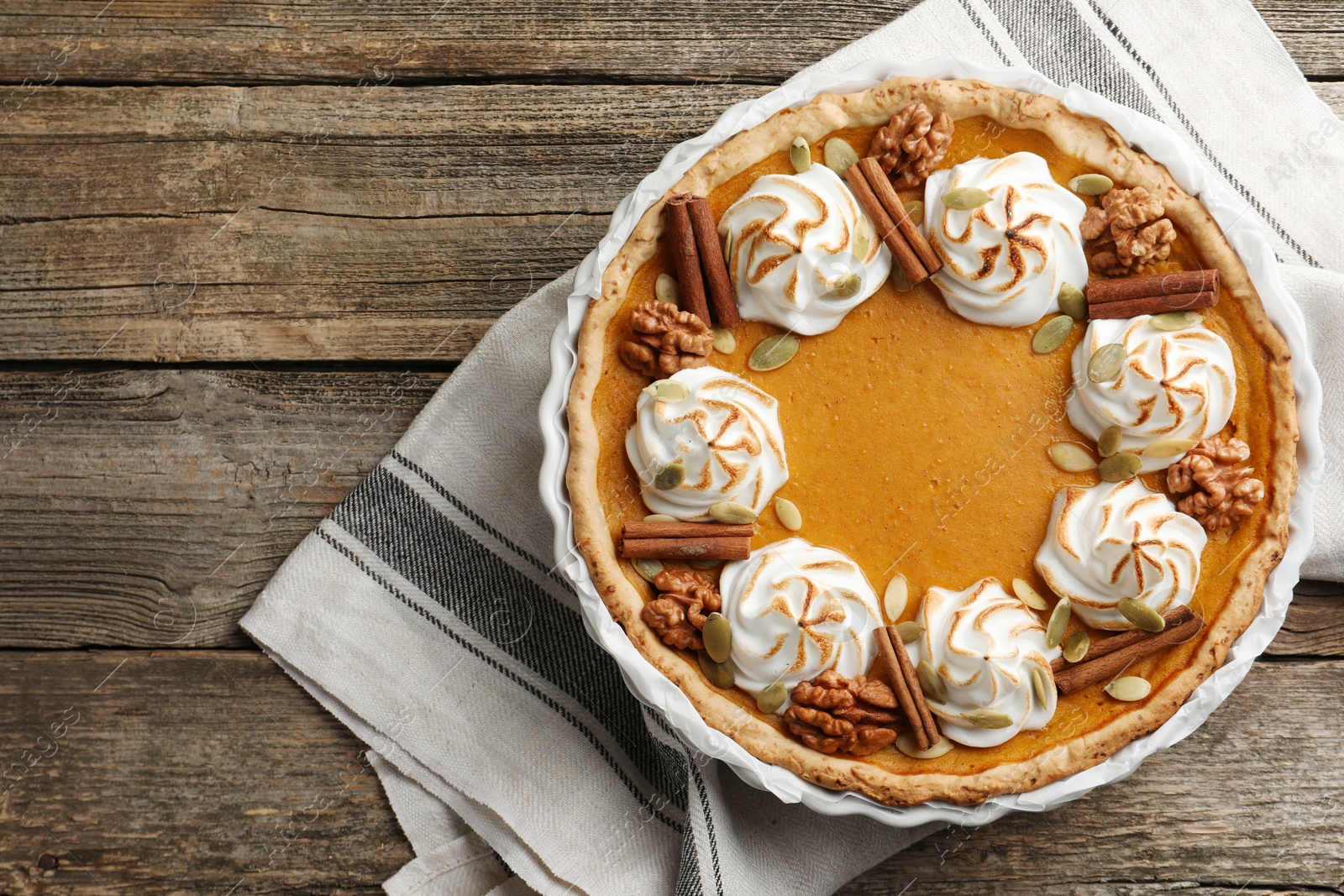 Photo of Tasty homemade pumpkin pie in baking dish on wooden table, top view. Space for text