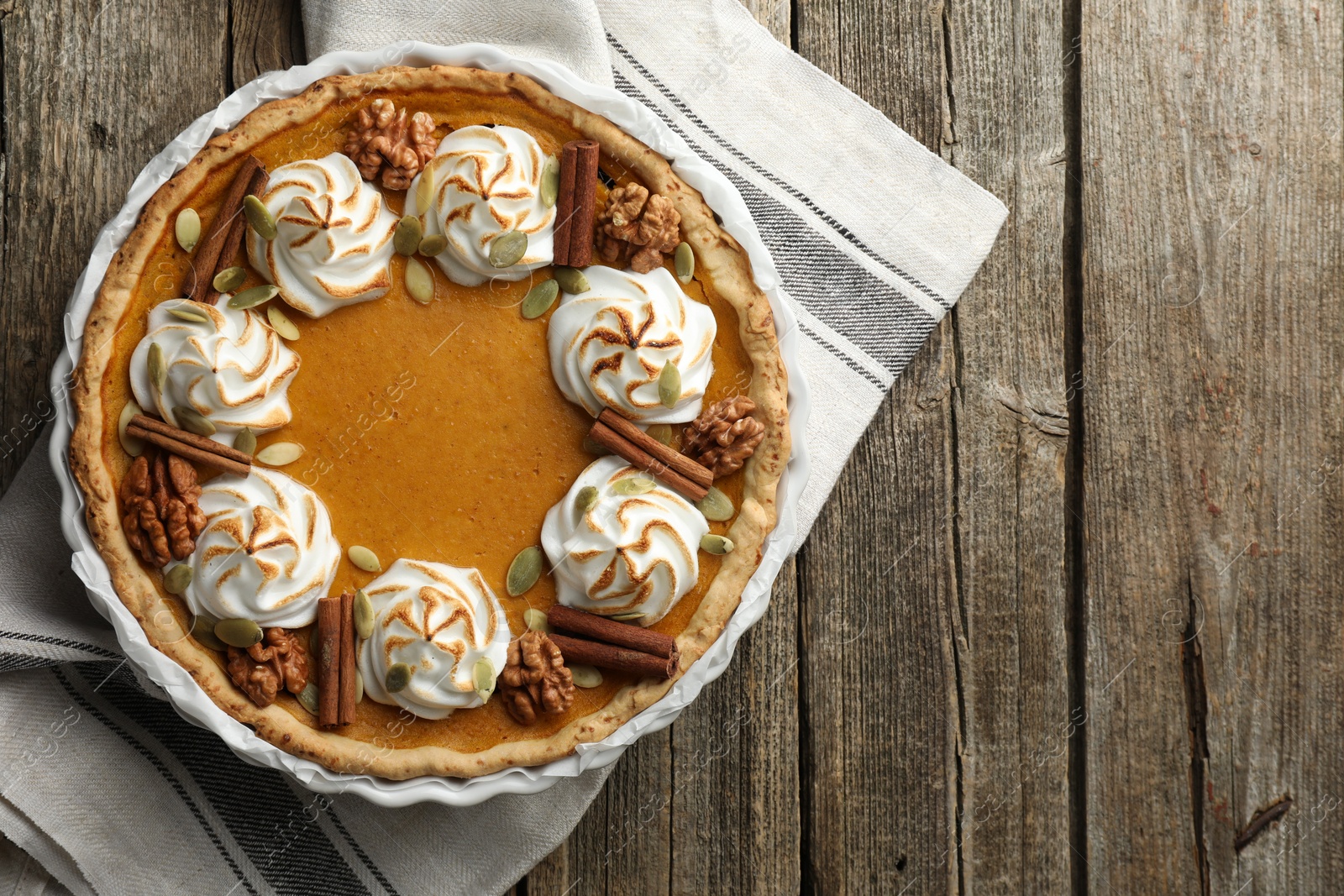 Photo of Tasty homemade pumpkin pie in baking dish on wooden table, top view. Space for text