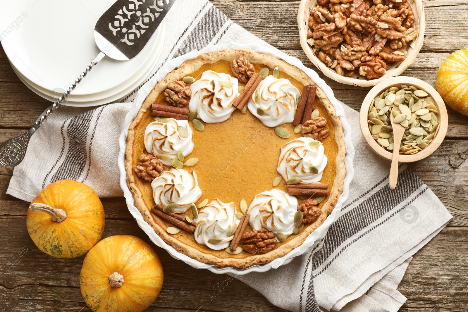 Photo of Tasty homemade pumpkin pie in baking dish and ingredients on wooden table, flat lay