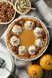 Photo of Tasty homemade pumpkin pie in baking dish and ingredients on wooden table, flat lay