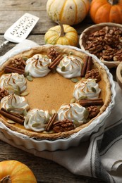 Photo of Tasty homemade pumpkin pie, ingredients and cake server on wooden table, closeup