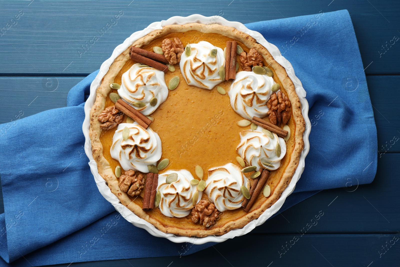 Photo of Delicious homemade pumpkin pie in baking dish on blue wooden table, top view