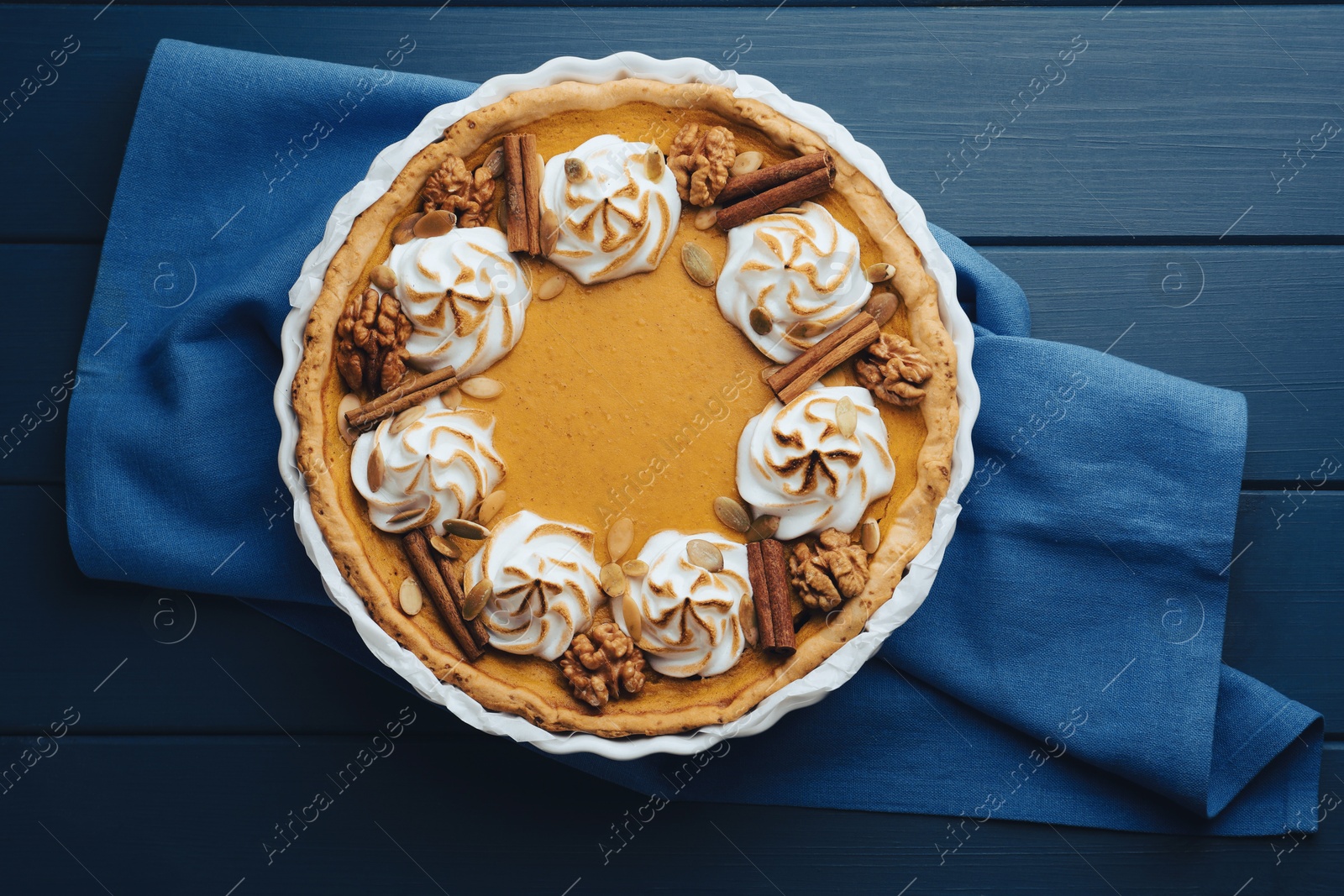 Photo of Delicious homemade pumpkin pie in baking dish on blue wooden table, top view