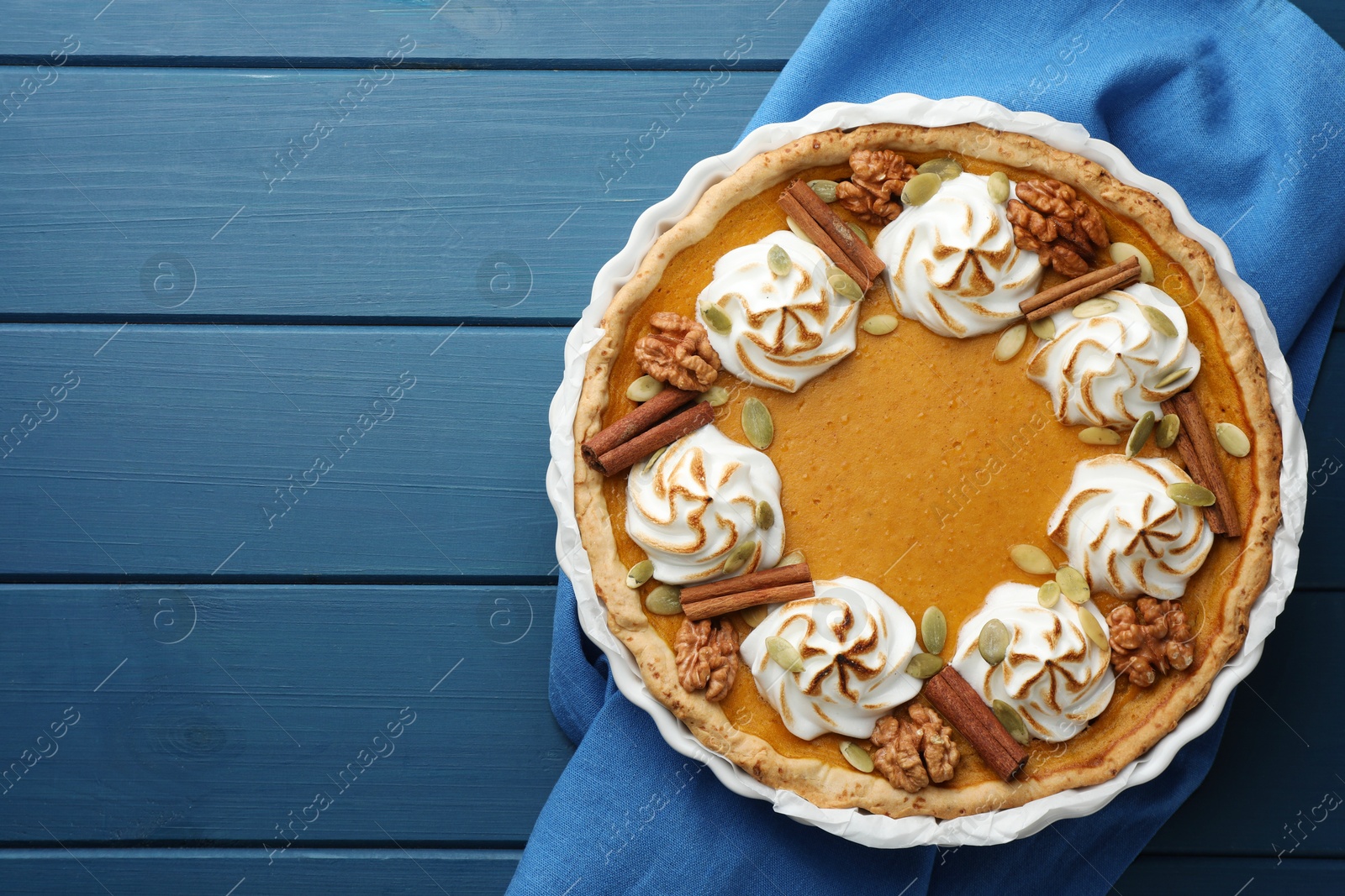 Photo of Delicious homemade pumpkin pie in baking dish on blue wooden table, top view. Space for text