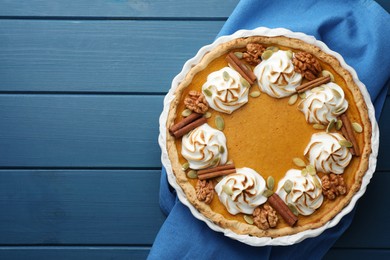 Delicious homemade pumpkin pie in baking dish on blue wooden table, top view. Space for text