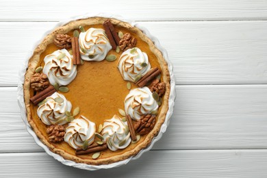 Delicious homemade pumpkin pie in baking dish on white wooden table, top view. Space for text