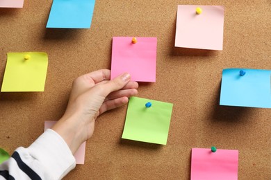 Photo of Woman holding paper note pinned to cork board, closeup