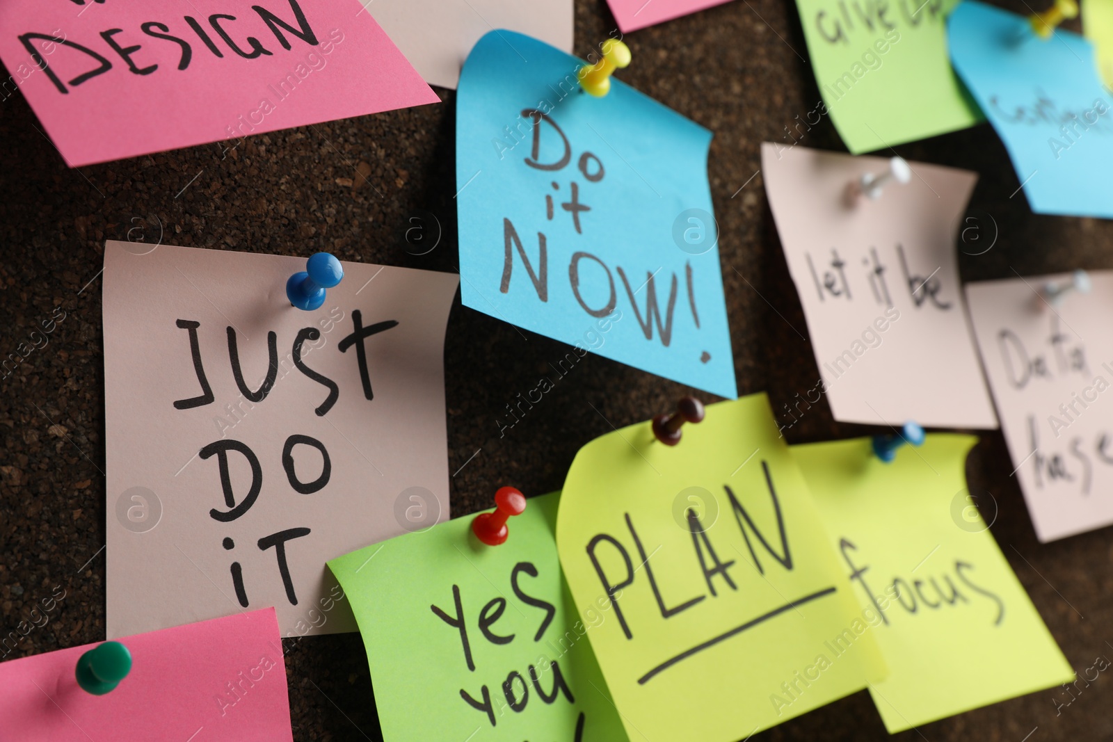 Photo of Colorful reminder notes pinned to cork board, closeup