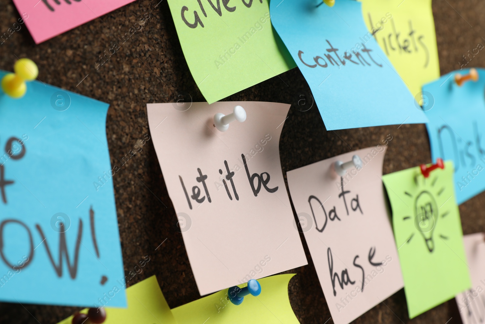 Photo of Colorful reminder notes pinned to cork board, closeup