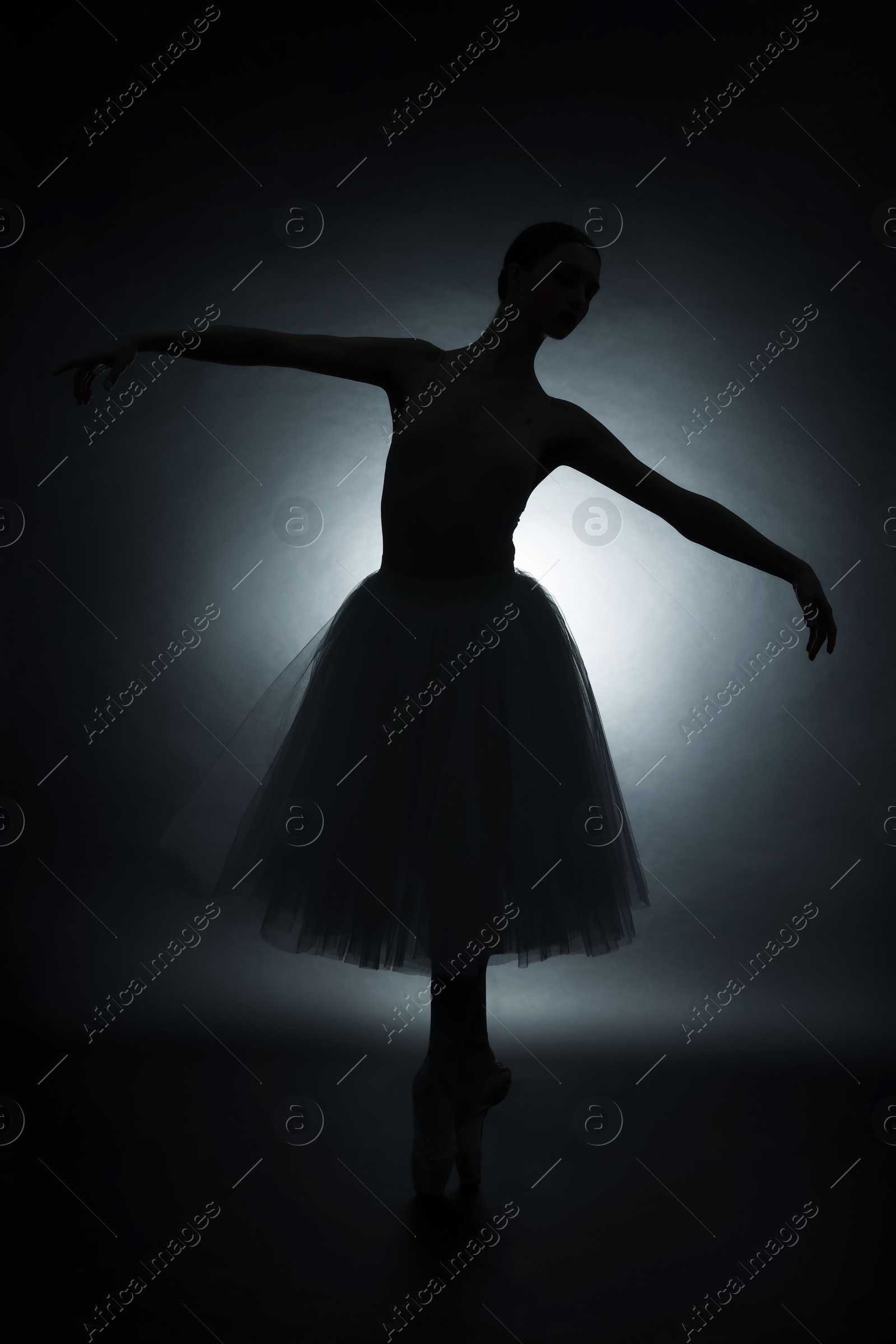 Photo of Young ballerina practicing dance moves on black background