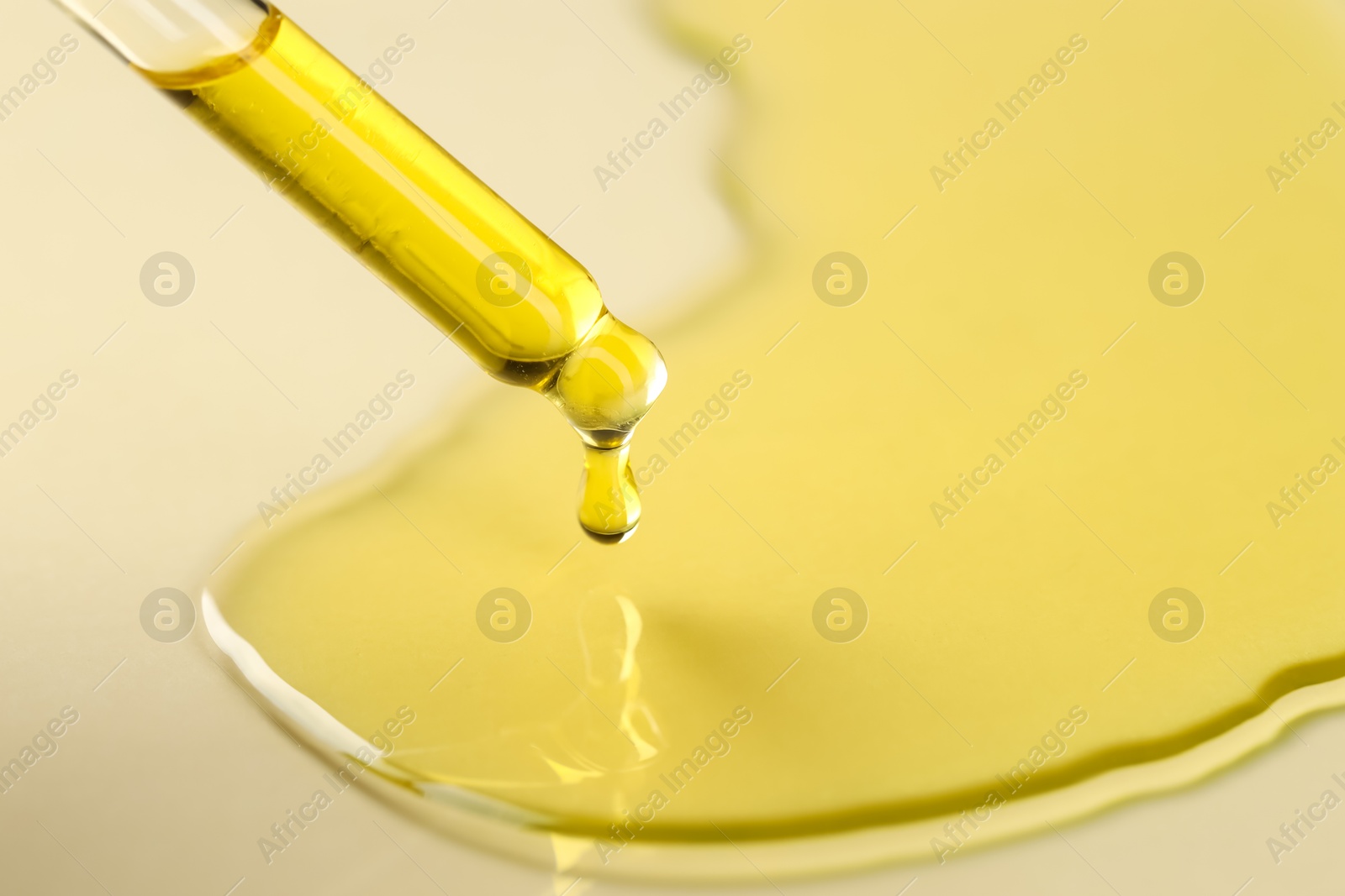 Photo of Cosmetic oil dripping from pipette on dark beige background, closeup. Space for text