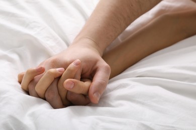 Photo of Lovely couple holding hands in bed, closeup