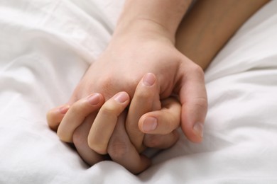 Lovely couple holding hands in bed, closeup