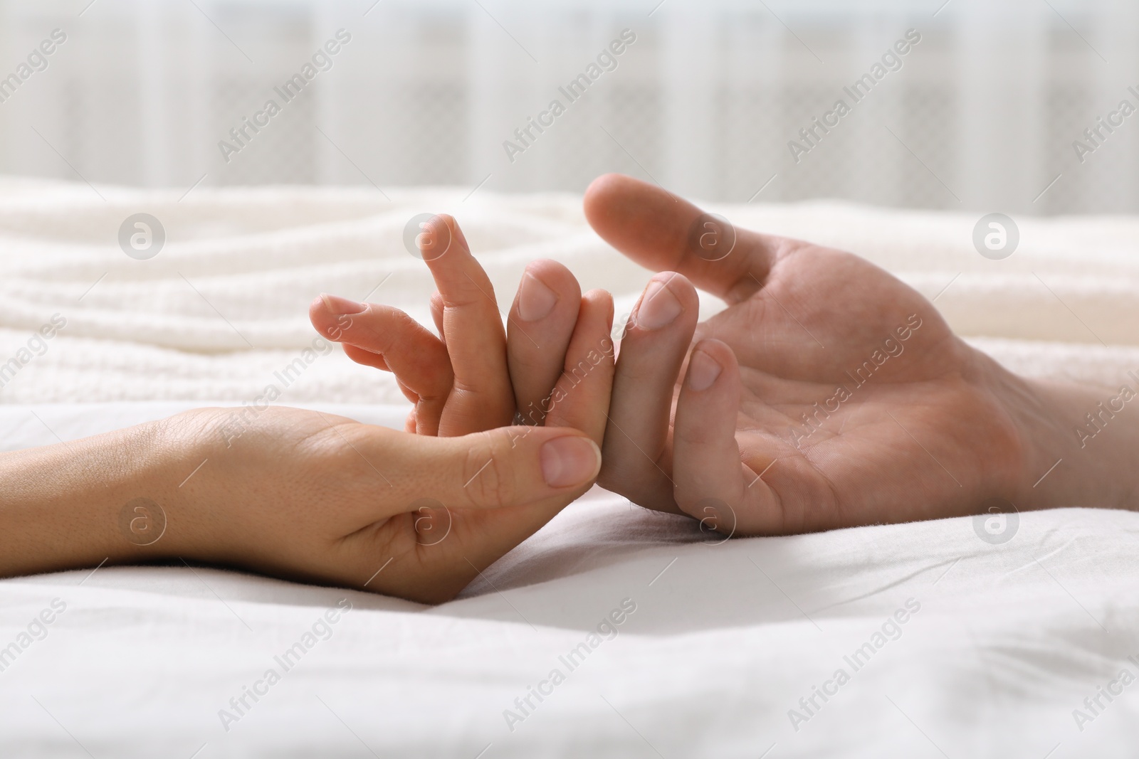 Photo of Lovely couple holding hands in bed, closeup