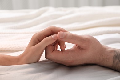 Photo of Lovely couple holding hands in bed, closeup