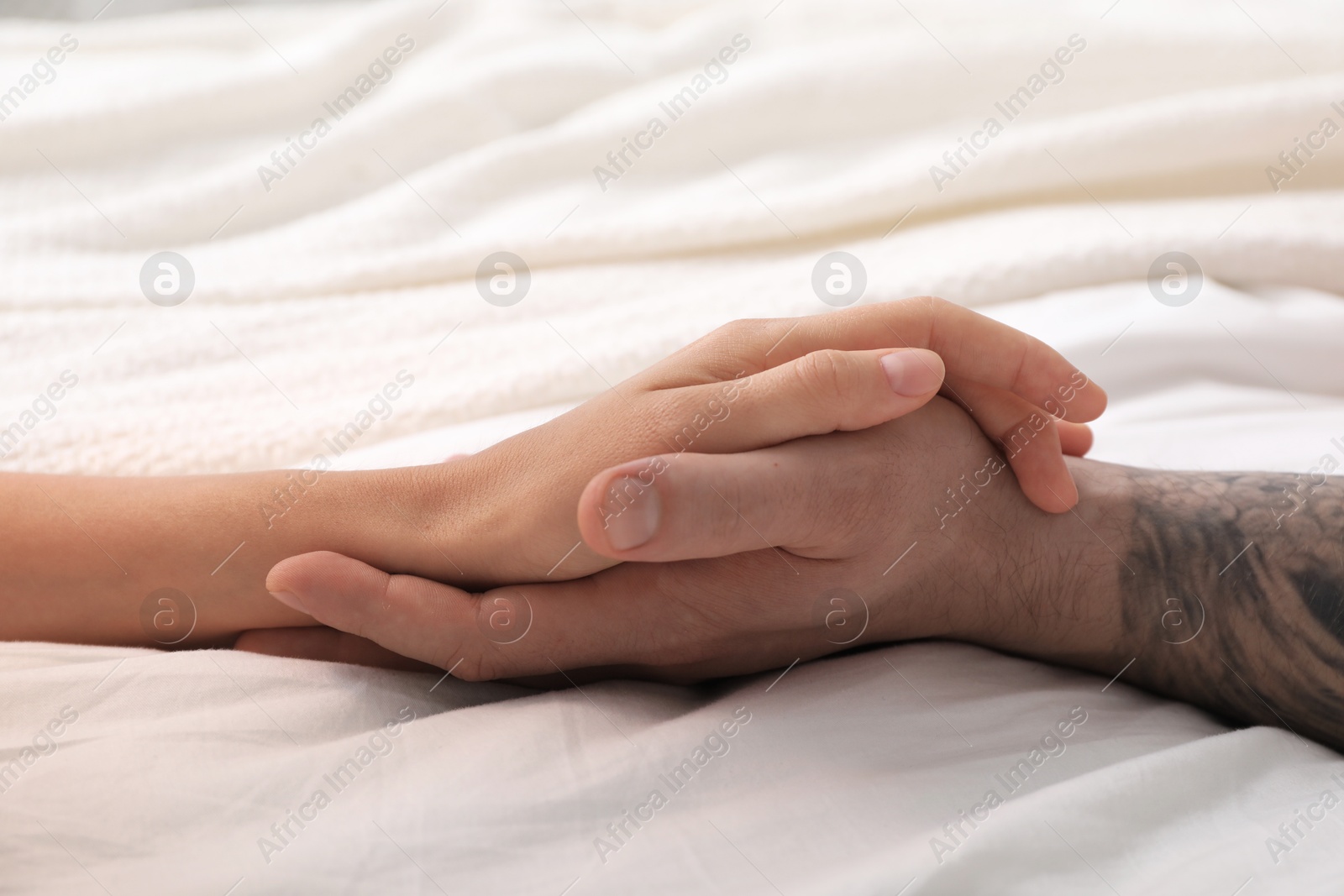 Photo of Lovely couple holding hands in bed, closeup