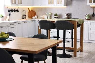 Photo of Bar stools, tables and other furniture in stylish kitchen