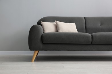 Photo of Comfortable sofa with cushions near grey wall in room