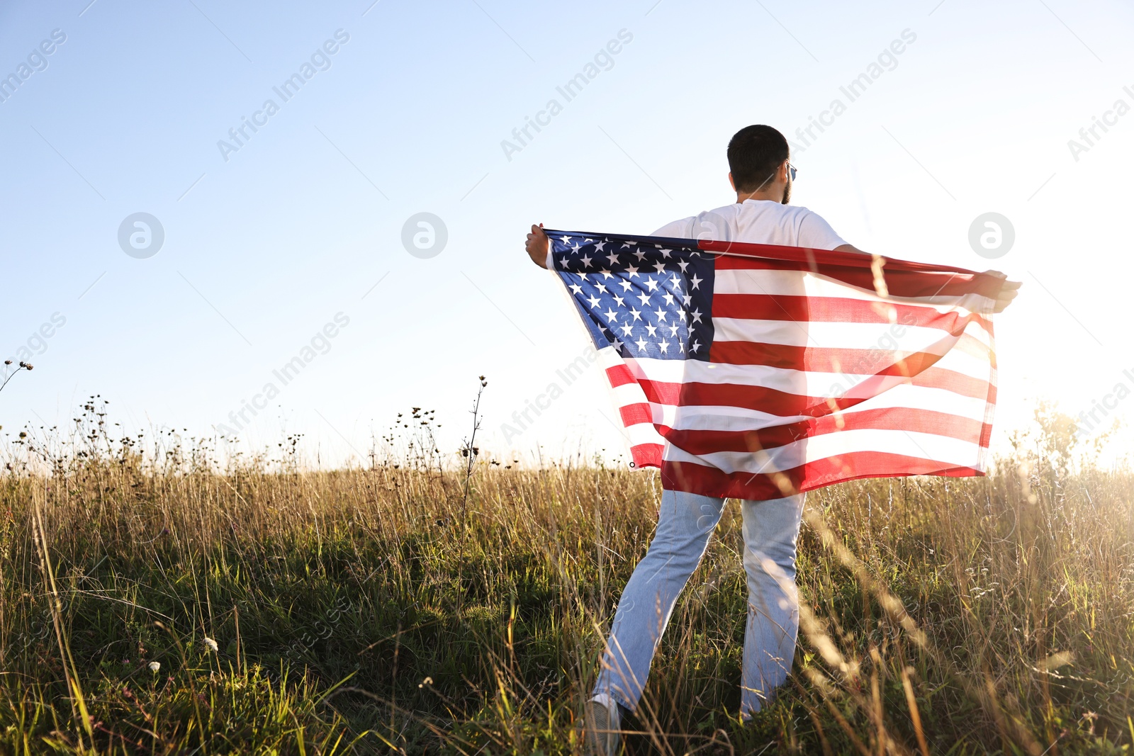 Photo of Man with flag of USA outdoors, back view. Space for text