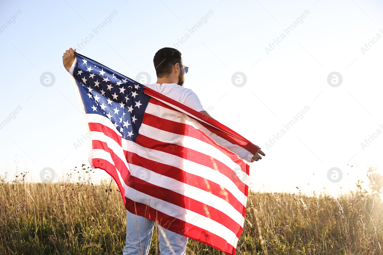 Photo of Man with flag of USA outdoors, back view