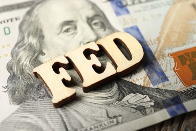 Photo of Wooden letters Fed (Federal Reserve System) and dollar banknote on table, closeup