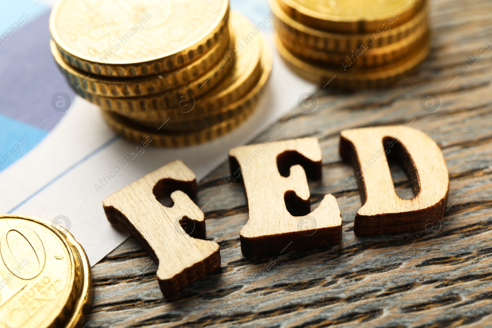 Photo of Letters Fed (Federal Reserve System) and coins on wooden table, closeup