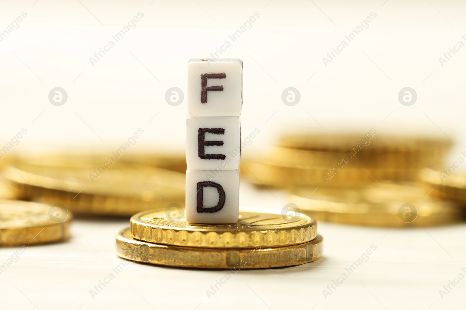 Photo of Cubes with letters Fed (Federal Reserve System) and coins on white table, closeup