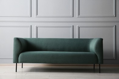 Photo of One stylish sofa near grey wall indoors