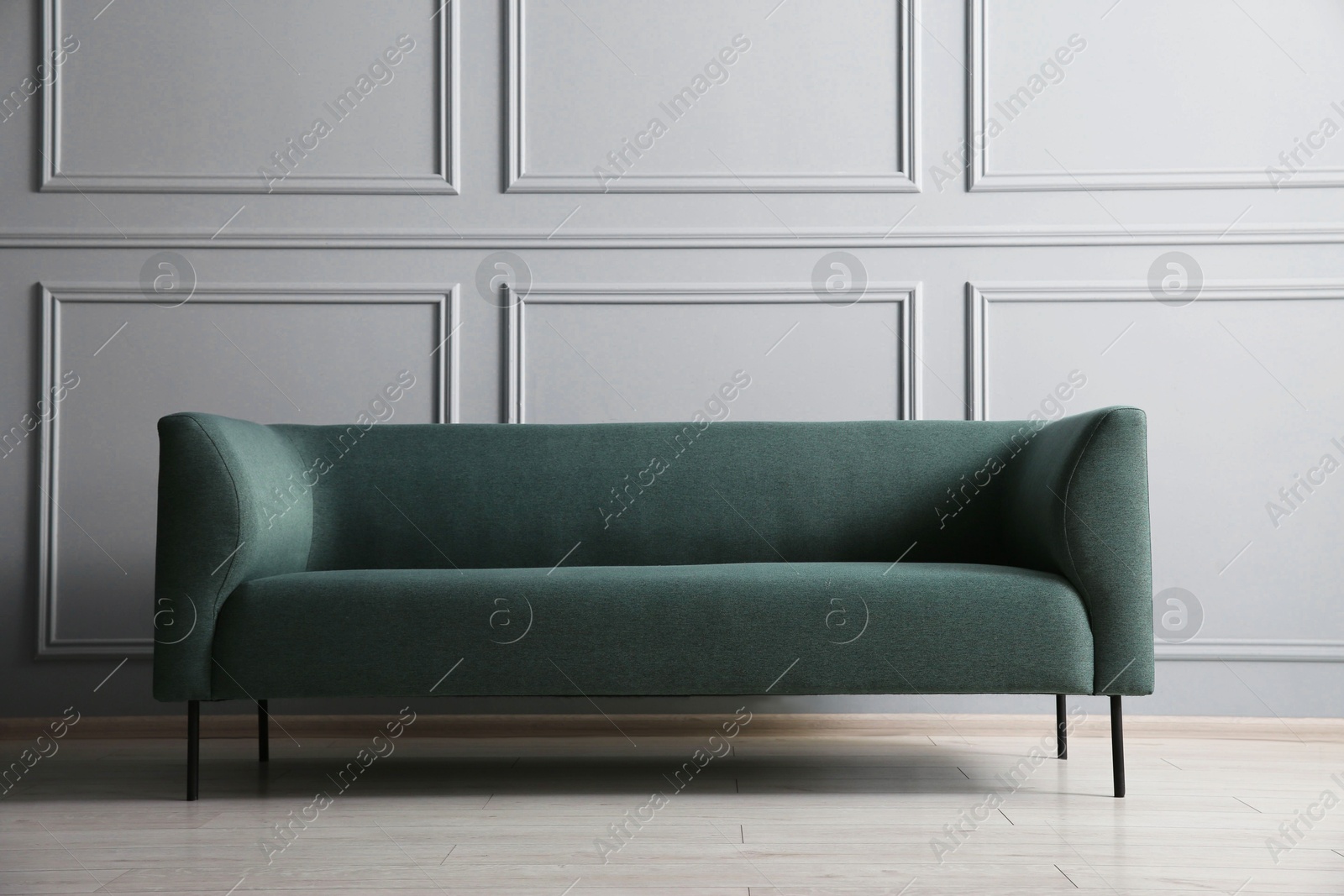 Photo of One stylish sofa near grey wall indoors