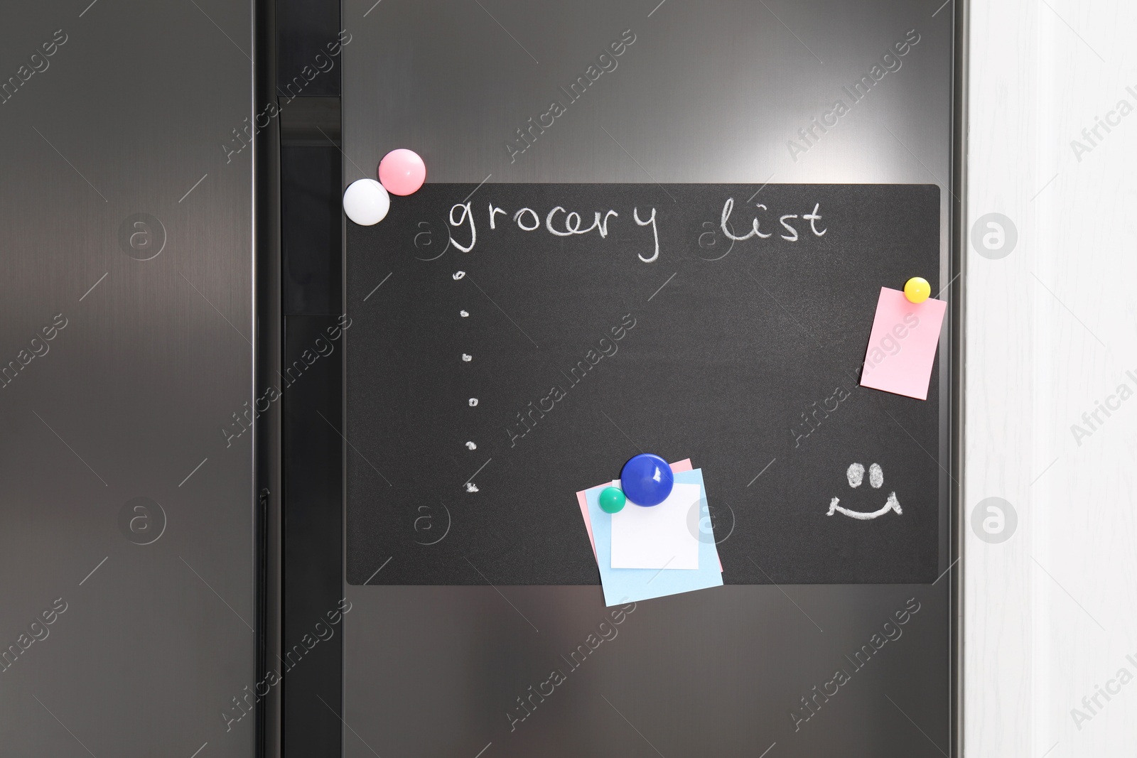 Photo of Magnetic board with grocery list and notes on refrigerator in kitchen