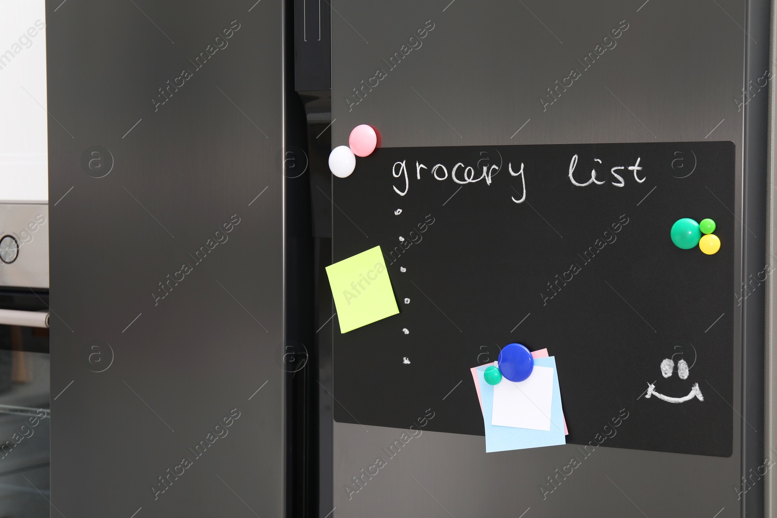 Photo of Magnetic board with grocery list and notes on refrigerator in kitchen