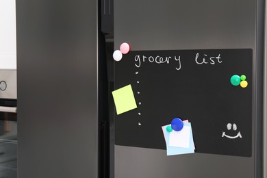 Photo of Magnetic board with grocery list and notes on refrigerator in kitchen