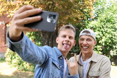 Happy brothers taking selfie and gesturing outdoors