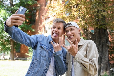 Photo of Happy brothers taking selfie and gesturing outdoors