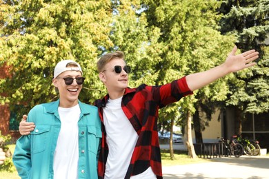 Photo of Handsome man showing something to his brother outdoors