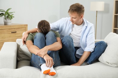 Young man comforting his brother at home